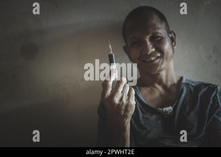 Drogenabhängiger Mann mit Halluzinationen, drogenabhängiger Mann mit Spritze, der Drogen verwendet. Stockfoto