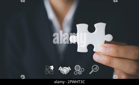 Hand halten Puzzle, Business Partnerschaft Konzept. Hände von Geschäftsleuten verbinden Puzzleteile auf dunklem Hintergrund. Geschäftskonzept Idee, teamw Stockfoto