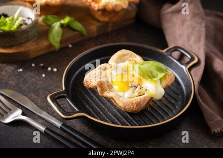 Rührei in Blätterteig mit Käse und Speck auf einem Steinteller. Frühstücksidee, Snacks. Stockfoto