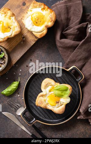 Rührei in Blätterteig mit Käse und Speck auf einem Steinteller. Frühstücksidee, Snacks. Blick von oben. Stockfoto