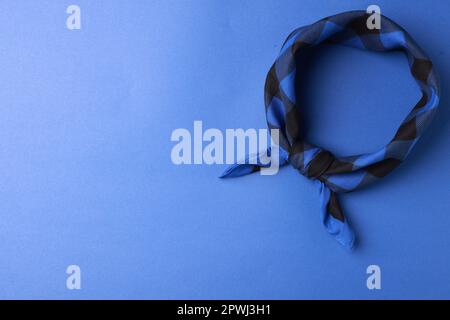 Gebundenes Bandana mit Karomuster auf blauem Hintergrund, Draufsicht. Platz für Text Stockfoto