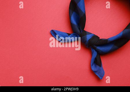 Gefliestes blaues Bandana mit Karomuster auf rotem Hintergrund, Draufsicht. Platz für Text Stockfoto