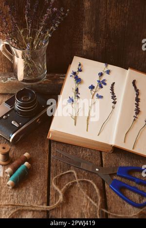Komposition mit schönen getrockneten Blumen und Vintage-Kamera auf Holztisch Stockfoto