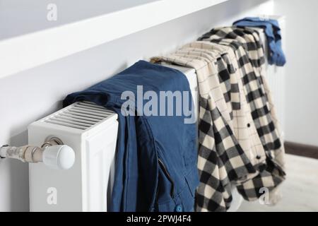 Die Kleidung hing auf dem weißen Heizkörper im Zimmer Stockfoto