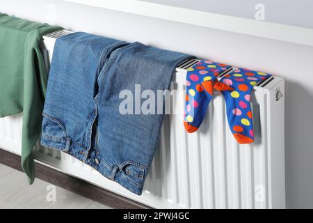 Die Kleidung hing auf dem weißen Heizkörper im Zimmer Stockfoto