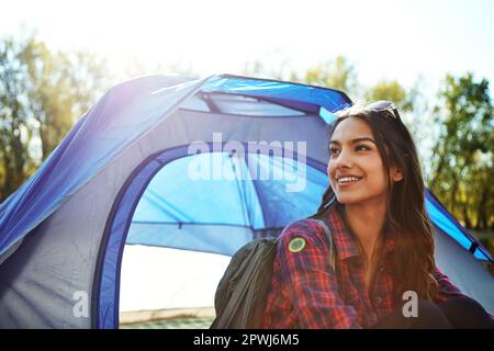 Sie entkommt allem. Eine attraktive junge Frau, die auf ihrem Campingplatz sitzt. Stockfoto