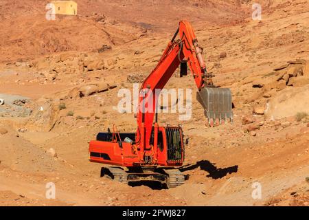 Orange Bagger arbeitet auf einer Baustelle in der Wüste auf der Sinai-Halbinsel, Ägypten Stockfoto