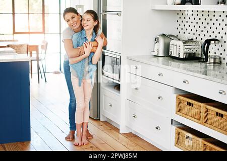 Mütter lieben. Es gibt nichts Vergleichbares. Eine glückliche Mutter und Tochter in einer liebevollen Umarmung zu Hause. Stockfoto