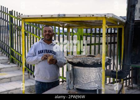 Umm Qais, Jordanien Oktober 25 2022: Anbieter, der Erdnüsse in einem Marktstand in den Ruinen von Gadara röstet und verkauft. Stockfoto