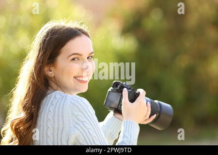 Ein glücklicher Fotograf im Park sieht dich mit der Kamera an Stockfoto