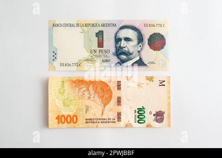 Zwei argentinische Peso-Scheine. Einer von einem Peso, gedruckt 1992, ein weiterer von eintausend, gedruckt 2020. Inflation, Abwertungskonzept. Stockfoto