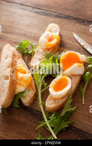 Gekochte Eier auf krustendem Baguette mit frischem Grün für ein gesundes Frühstück oder einen Snack aus nächster Nähe mit Blick aus einem hohen Winkel Stockfoto