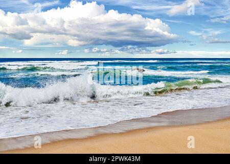 Wellen Rollen und stürzen an einem Sommertag am Strand ab. Meer, Meeresströmung und Gezeiten, die unter einer bewölkten Bucht an das Meer gelangen Stockfoto