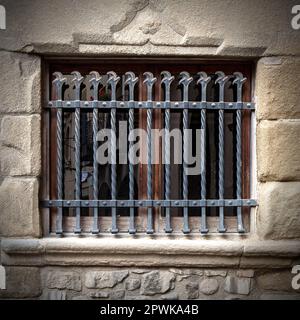 Metallgitter an einem alten Fenster in einem Steingebäude Stockfoto