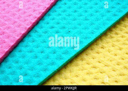 Ein Satz Reinigungstücher, Mikrofasertücher oder Schwämme für die Küche, drei mehrfarbige Tücher. Schaumstofffasern Schwamm Texturmuster Oberfläche nahe- Stockfoto