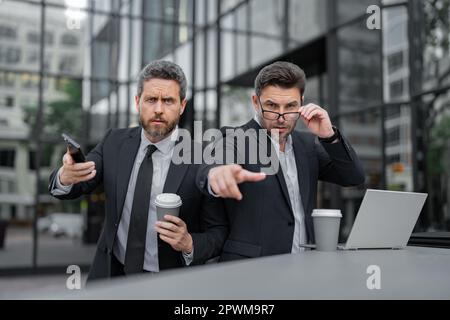 Ausdrucksgesicht eines emotionalen Geschäftsmannes. Ein seriöser Geschäftsmann, der mit dem Finger auf Sie zeigt. Die beiden Business-Teams arbeiteten zusammen, um ihre Ziele zu erreichen Stockfoto