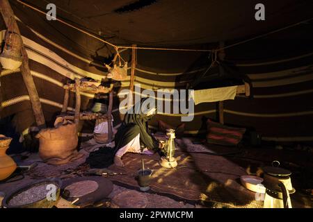 Eine Wüstenstämmerin in einem Zelt, die Kerosin-Laternen für die Nacht anzündet. Ein Diorama mit einer Szene aus der Vergangenheit der Vereinigten Arabischen Emirate im Abu Dhabi History Museum Stockfoto