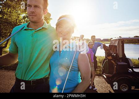 Das Spiel, das sie näher brachte. Zwei Paare, die an einem sonnigen Tag eine Runde Golf spielen. Stockfoto