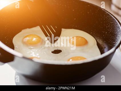 Person, die in der Bratpfanne zum Frühstück Spiegeleier zubereitet. Stockfoto