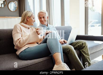 Jeder verdient es, sich im Ruhestand zu entspannen. Ein reifes Paar, das zu Hause einen Laptop auf dem Sofa benutzt Stockfoto