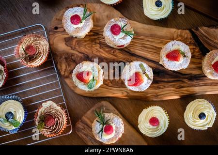 Wunderschöne Mini-Victoria-Schwämme und Cupcakes auf gewürzten Holzbrettern Stockfoto