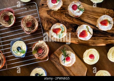 Wunderschöne Mini-Victoria-Schwämme und Cupcakes auf gewürzten Holzbrettern Stockfoto