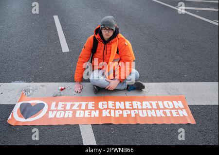 28.04.2023, Berlin, Deutschland, Europa - Klimaprotester der so genannten Letzte Generation hat sich auf Asphalt einer Straße geklebt. Stockfoto