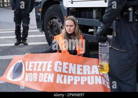 28.04.2023, Berlin, Deutschland, Europa - Eine Klimaprotestierende der so genannten Letzten Generation (Letzte Generation) hat sich auf einen Asphalt einer Straße geklebt. Stockfoto