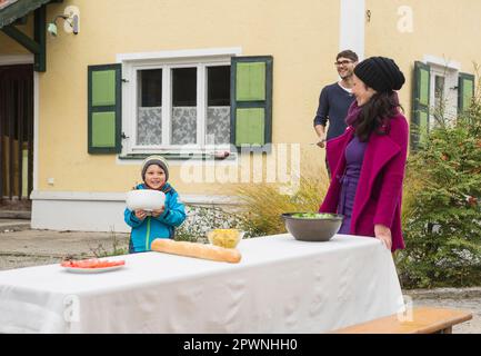 Die Familie bereitet draußen einen Picknicktisch im Bauernhaus in Bayern vor Stockfoto