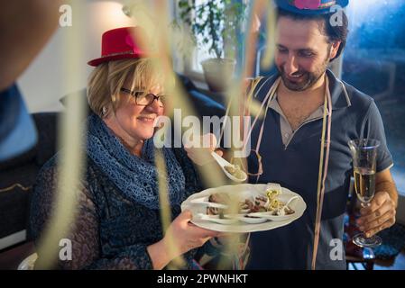 Eine Frau, die Gästen auf einer Party Essen anbietet Stockfoto