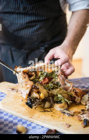 Koch beim Schnitzen einer gerösteten Ente mit Gemüsefüllung Stockfoto