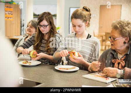 Seniorinnen mit Mädchen, die Apfel schälen Stockfoto