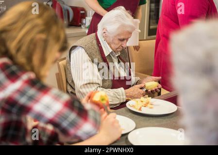 Seniorinnen mit Mädchen, die Apfel schälen Stockfoto