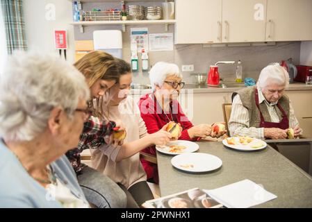 Seniorinnen mit Mädchen, die Apfel schälen Stockfoto