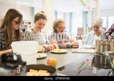 Seniorinnen mit Mädchen, die Apfel schälen Stockfoto