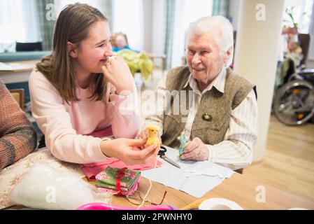 Seniorin mit einem Mädchen, das ein handgemachtes Häkelmädchen in einem Heim hält Stockfoto