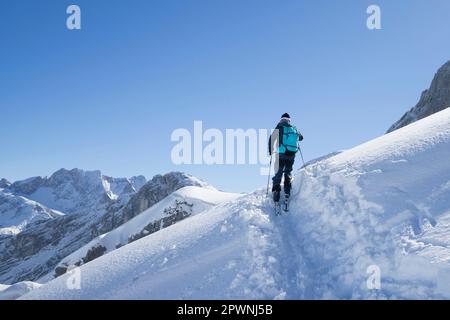 Blick aus dem niedrigen Winkel auf Skifahrer, die die Skipiste besteigen, Bayern, Deutschland, Europa Stockfoto