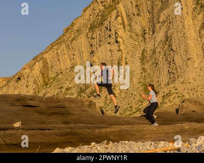 Mann und Frau, die auf einem einzigen Pfad auf der Klippe von Getxo laufen Stockfoto