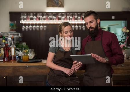 Zuversichtliche Restaurantbesitzer diskutieren, während sie ein digitales Tablet verwenden Stockfoto