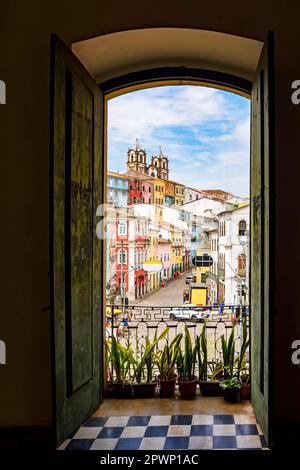 Offene Tür in einem alten Kolonialhaus mit Blick auf das Viertel Pelourinho und seine Hügel in Salvador, Bahia Stockfoto