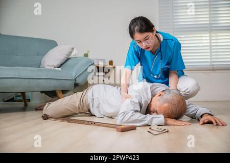 Asiatischer älterer Mann fiel auf den Boden und eine Krankenschwester kam, um zu helfen, behinderter älterer Mann Patient fiel hinunter und pflegte junge A. Stockfoto