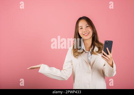 Happy Asian Portrait schöne niedliche junge Frau aufgeregt halten Handy leeren Bildschirm präsentiert Produkt mit Handfläche bei leer, Studio Schuss ich Stockfoto