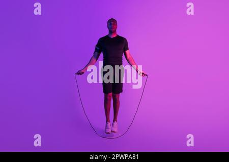 Schwarzer Sportler Mit Springseil Beim Workout, Lilafarbener Hintergrund Stockfoto