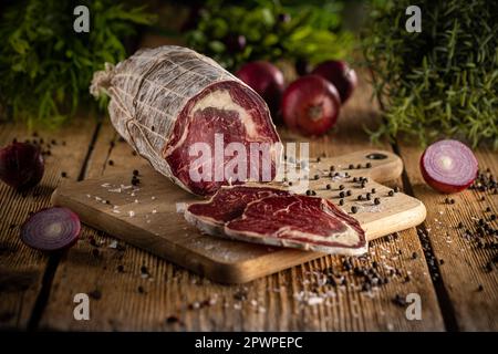 Getrocknetes und geräuchertes Rindfleisch in edlem Schimmelmantel auf Holzhintergrund Stockfoto