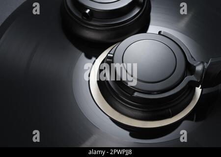 Vinyl-Schallplatte mit schwarzen Kopfhörern für Nahaufnahmen. Altes Musikkonzept. Stockfoto