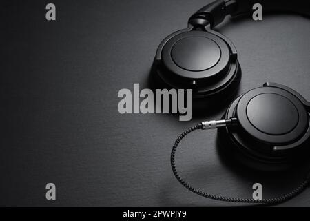 Kopfhörer auf schwarzem Schreibtisch. Musikkonzept. Draufsicht mit Kopierbereich. Stockfoto