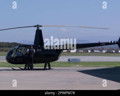 Zwei Touristen und ein Pilot gehen an Bord eines Hubschraubers, der einen Vergnügungsflug über Gwynedd und Anglesey vom Caernarfon Airport Gwynedd North Wales UK anbietet Stockfoto