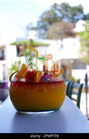 Großes kugelförmiges Glas für Kokzidiosen im Freien auf dem Bartisch im Sommer. Bokeh mit Stühlen im Hintergrund. Stockfoto