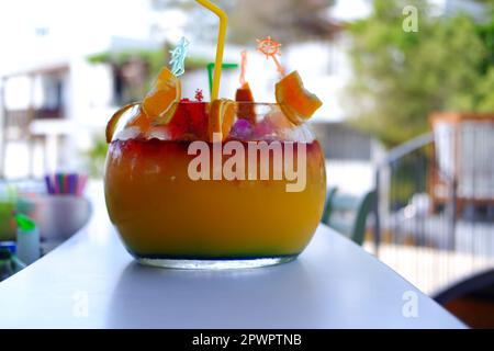 Großes kugelförmiges Glas für Kokzidiosen im Freien auf dem Bartisch im Sommer. Bokeh mit Stühlen im Hintergrund. Stockfoto