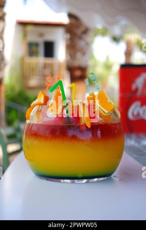 Großes kugelförmiges Glas für Kokzidiosen im Freien auf dem Bartisch im Sommer. Bokeh mit Stühlen im Hintergrund. Stockfoto